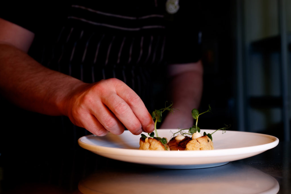 food and drink photography. A chef places some garnish onto a dish in this close up photograph