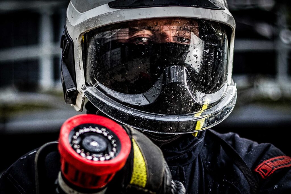 Commercial Photographer Aberdeen - Scott Cameron Baxter. Image shows a man during a offshore survival fire training course holding a hose with a wet helmet and visor.