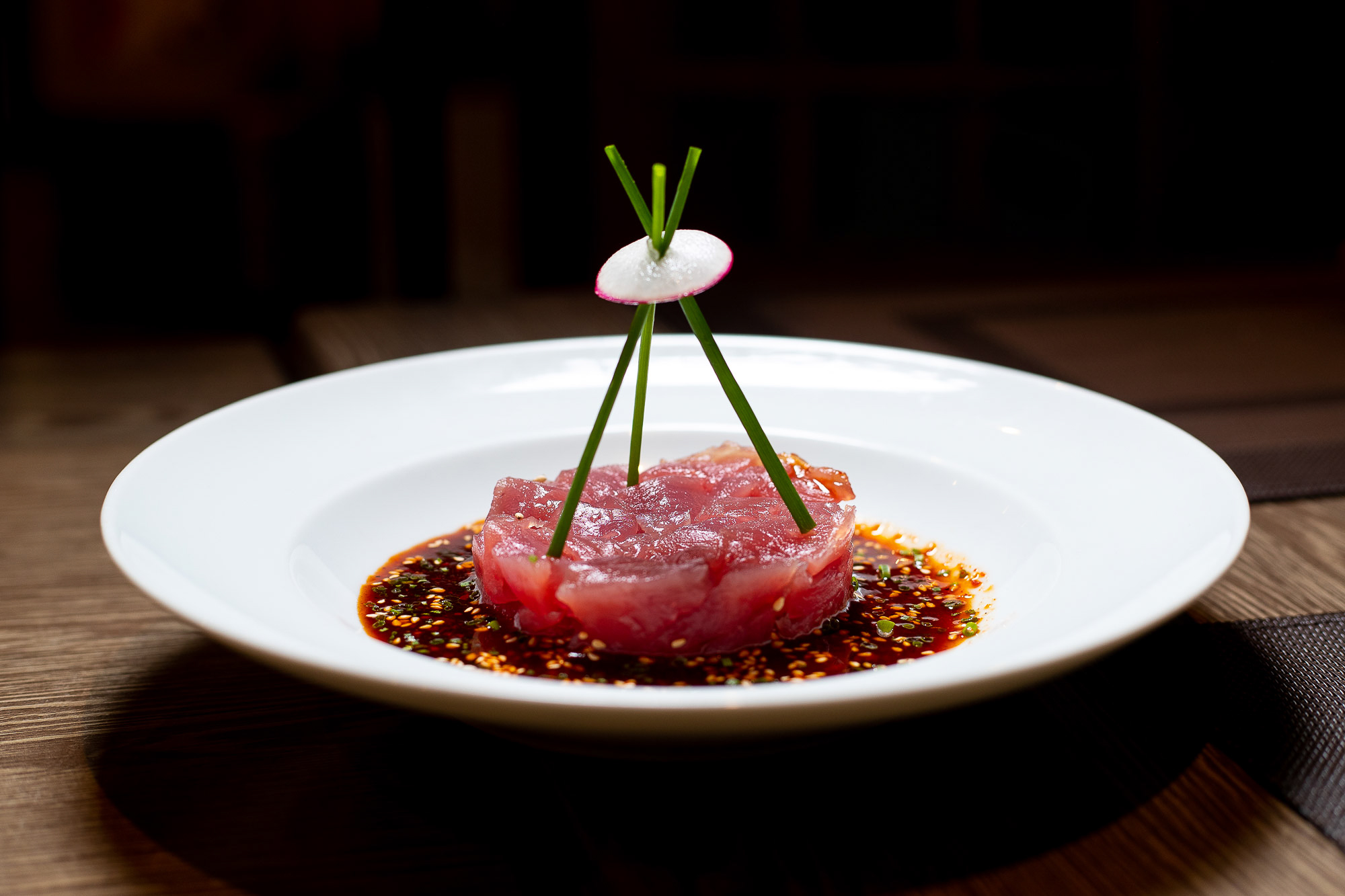 Tuna Tartare presented with chilli and a three spring onion structure which meet 5 inches above the plate in the middle held together by a finely sliced raddish. Served on a white bowl plate. Aberdeen Food photographer Scott Cameron Baxter.